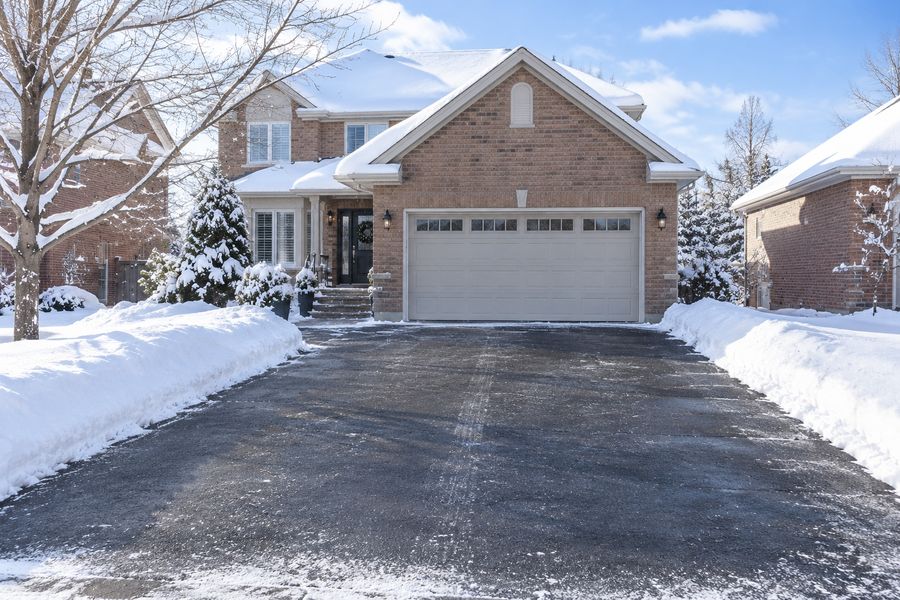 Cleared asphalt driveway in front of a brick home on a sunny winter day