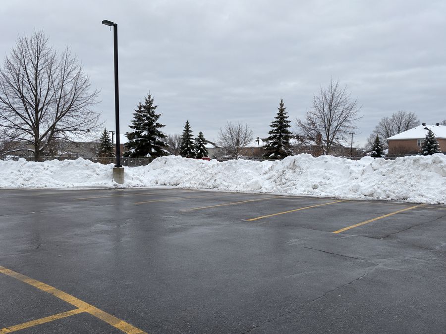 Plowed commercial parking lot with snow piled along the edge
